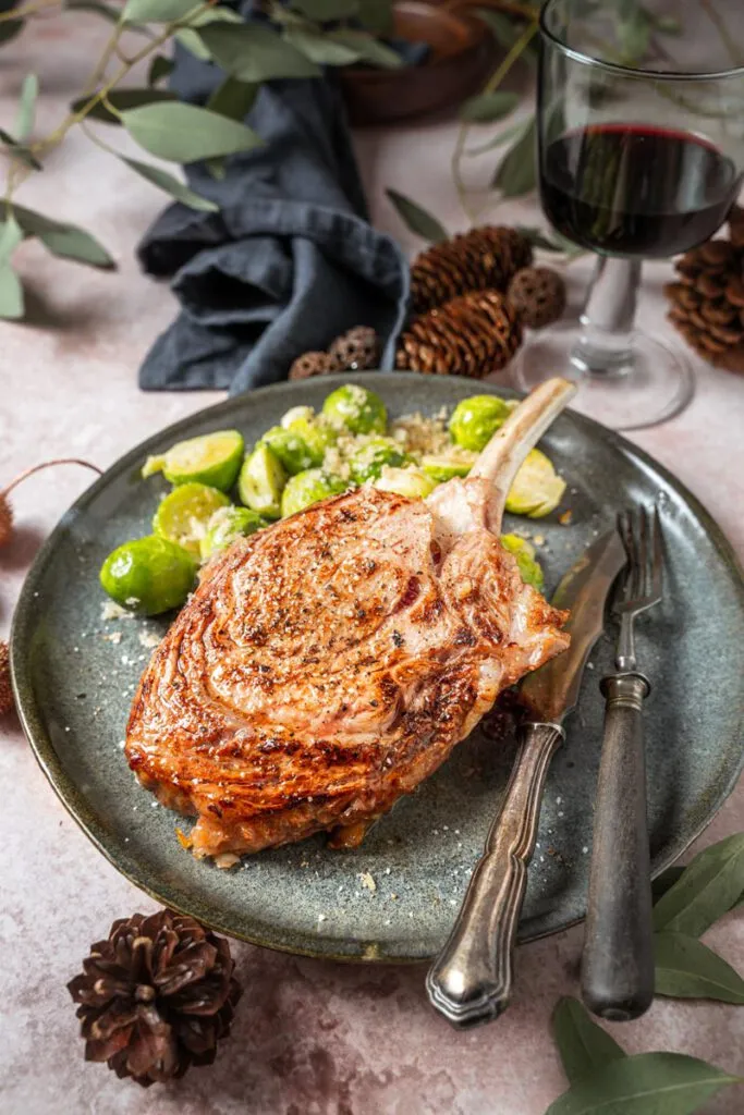 Kalbs-Tomahawk-Steak auf Schneidebrett mit Kräutern