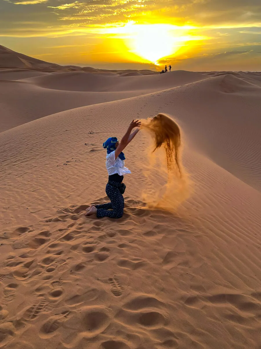 Kameltrekking in der Sahara bei Sonnenuntergang, mit einer Karawane auf den Sanddünen