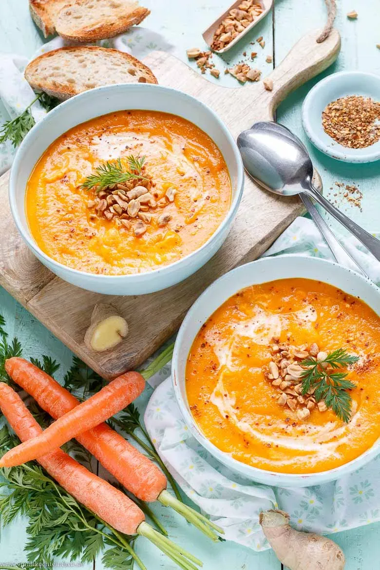 Karotten Ingwer Suppe im Suppenteller garniert mit Erdnüssen und Chiliflocken