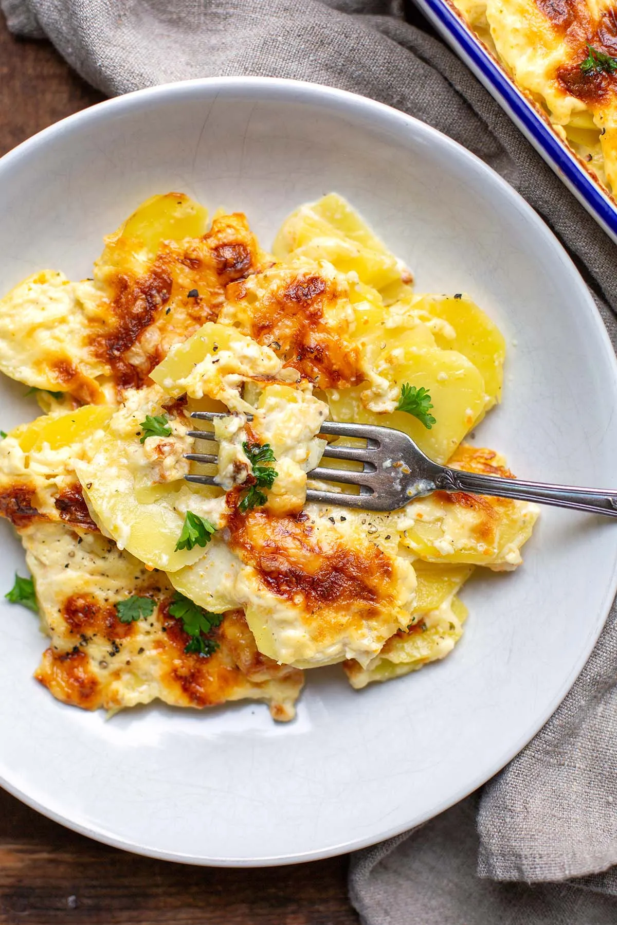 Kartoffelgratin auf einem weißen Teller mit einer Gabel.