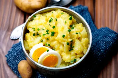 Kartoffelsalat mit Brühe und Eiern dekoriert in der Schüssel