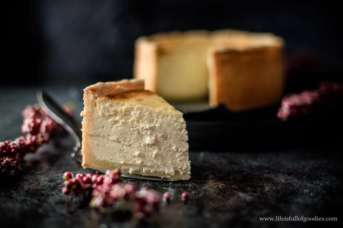 Käsekuchenstück mit Gabel auf weißem Teller, bereit zum Genuss
