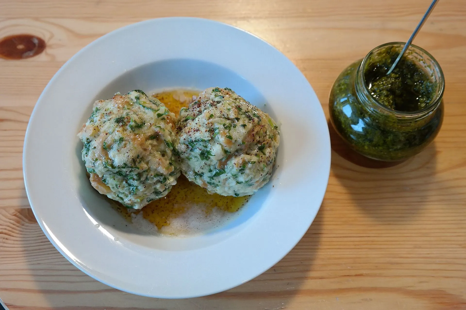 Käsknöpfle in einer Gusspfanne, verfeinert mit Röstzwiebeln und frischen Kräutern, dazu ein kleiner Beilagensalat, ein klassisches Gericht der alpenländischen Küche.