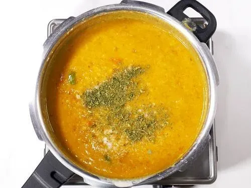 Kasuri Methi und Salz in das kochende Dal einrühren