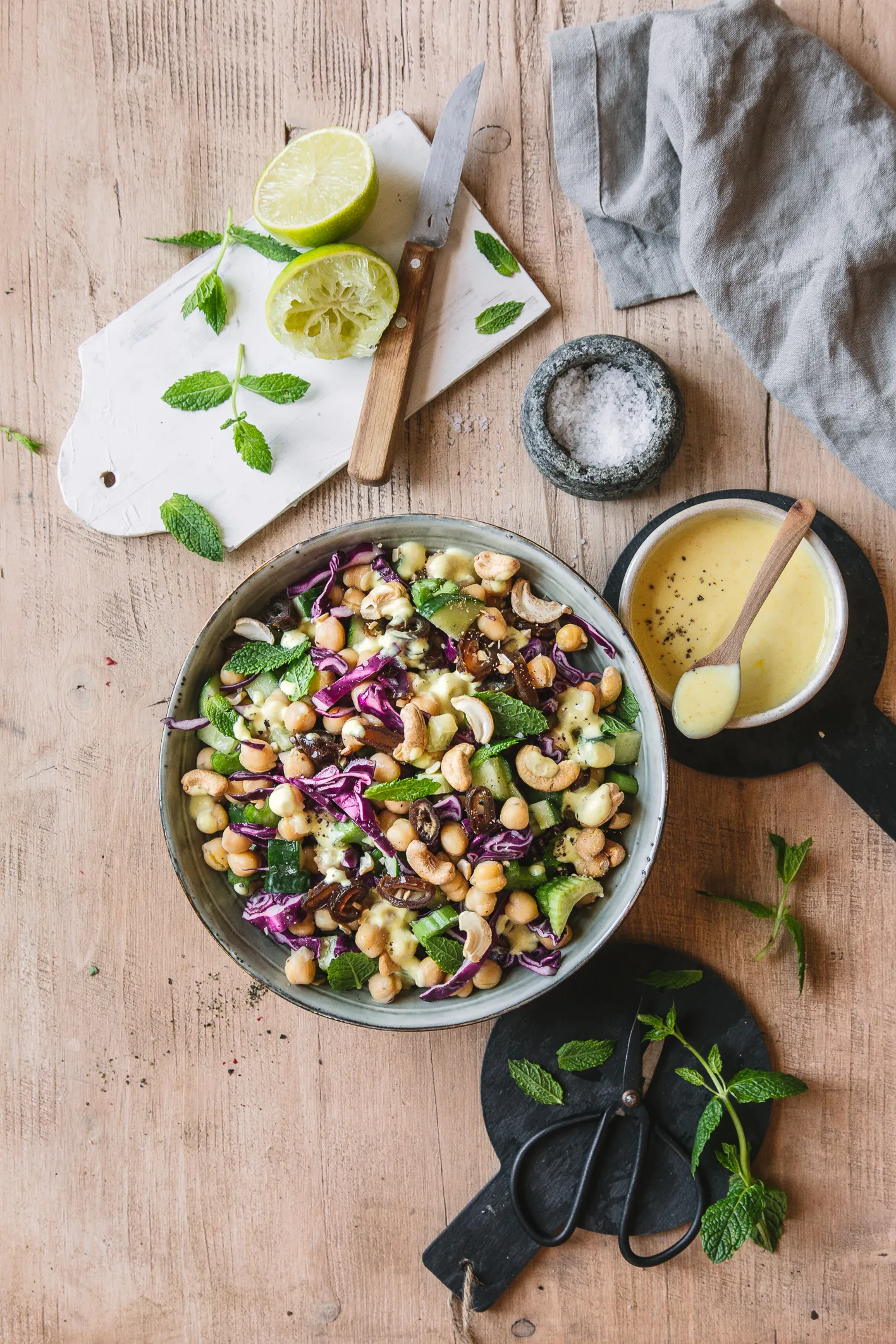 Kichererbsen-Rotkohl-Salat in Schüssel mit Dressing und Limetten auf Tisch