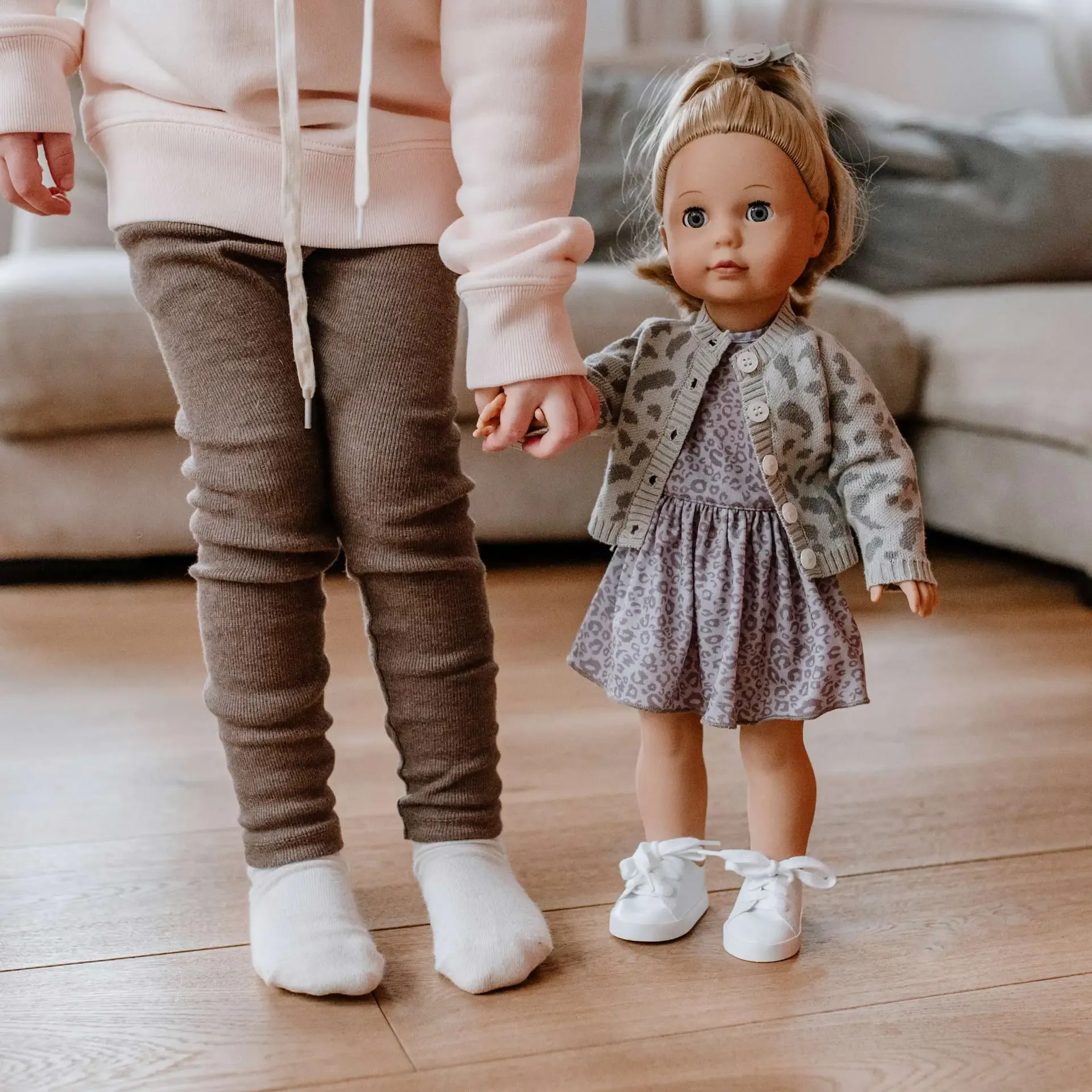 Kind hält die Hand einer Puppe mit Leopardenkleid.