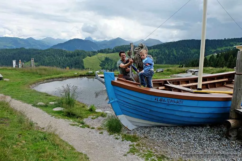 Kind klettert auf einem hölzernen Spielgerät auf einer Alm in den Kitzbüheler Alpen