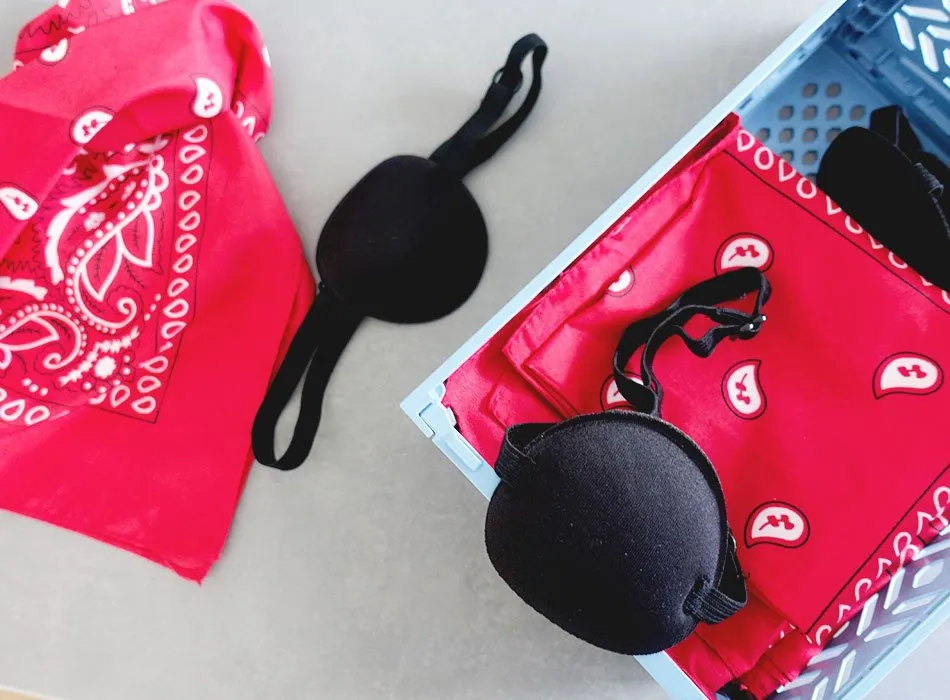 Kinder mit Augenklappen und Tüchern spielen eine spannende Piraten-Schatzsuche im Garten.