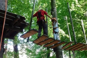 Kinder und Erwachsene beim gemeinsamen Klettern im Freiraum Kletterwald Freischütz, gefördert durch die AWO Familienbildungsstätte Schwerte im Rahmen des Familienpatenschaften-Projekts.