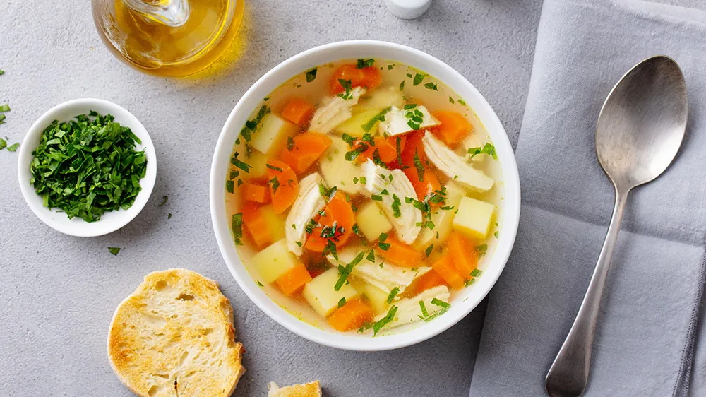 Klare Hühnerbrühe mit zarten Hähnchenstücken und frischem Gemüse als wärmende Suppe zum Abnehmen.