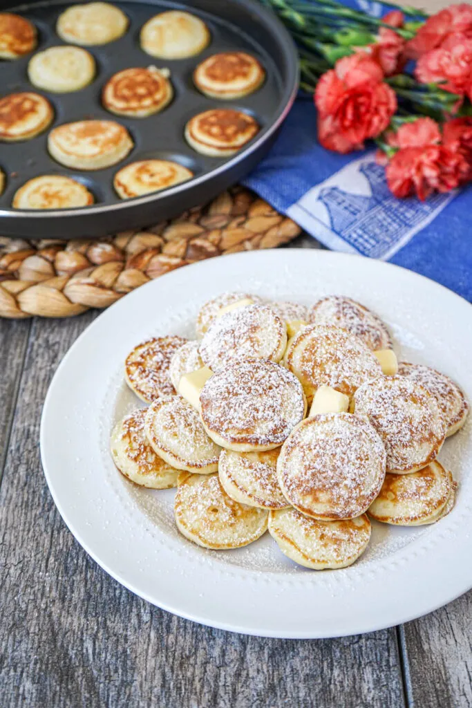 Klassisch servierte Poffertjes mit geschmolzener Butter und reichlich Puderzucker
