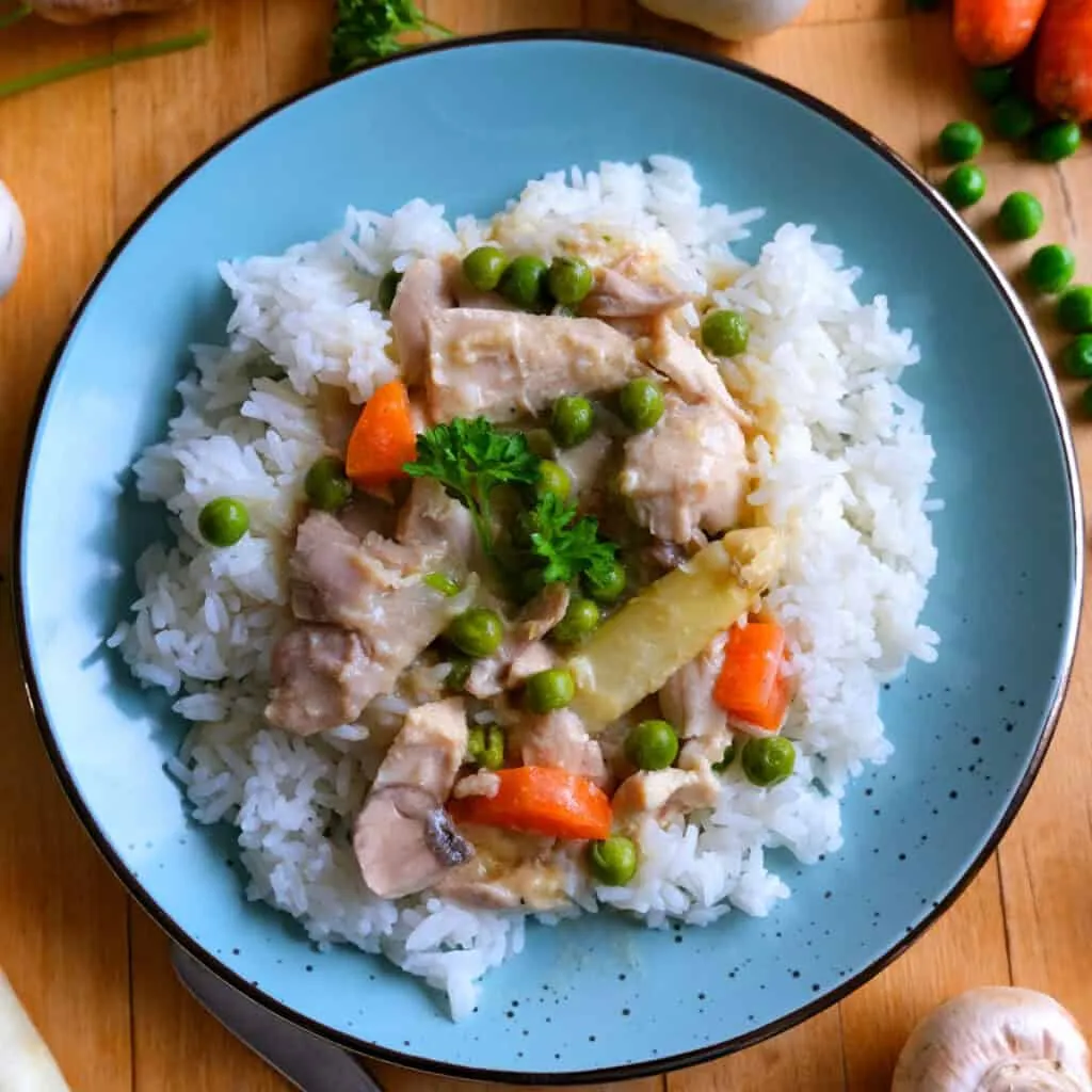 Klassisches Hühnerfrikassee in einer Schale serviert mit Reis und frischer Petersilie