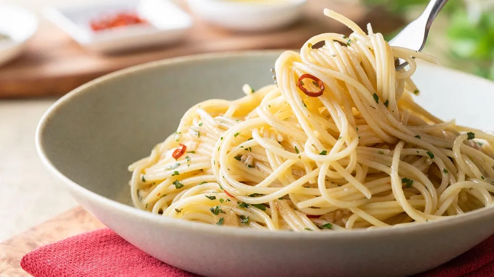 Knoblauch-Spaghetti im tiefen Teller und auf einer Gabel, bereit zum Genuss.