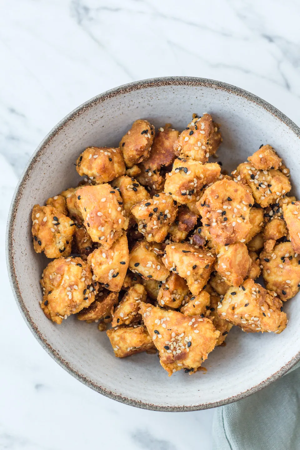 Knusprige Tofu-Stücke, perfekt gebraten und mariniert, garniert mit frischen Kräutern auf einem Teller.