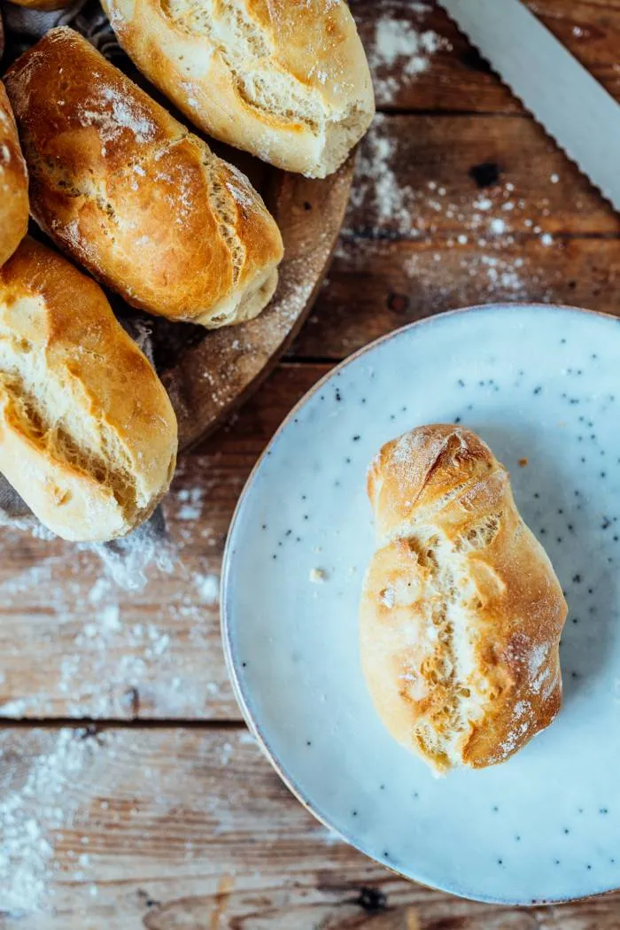 Korb voller selbstgemachter Baguette Brötchen auf einem Holztisch