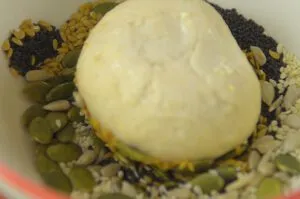 Körnerbrötchen werden in die Saatenmischung getaucht