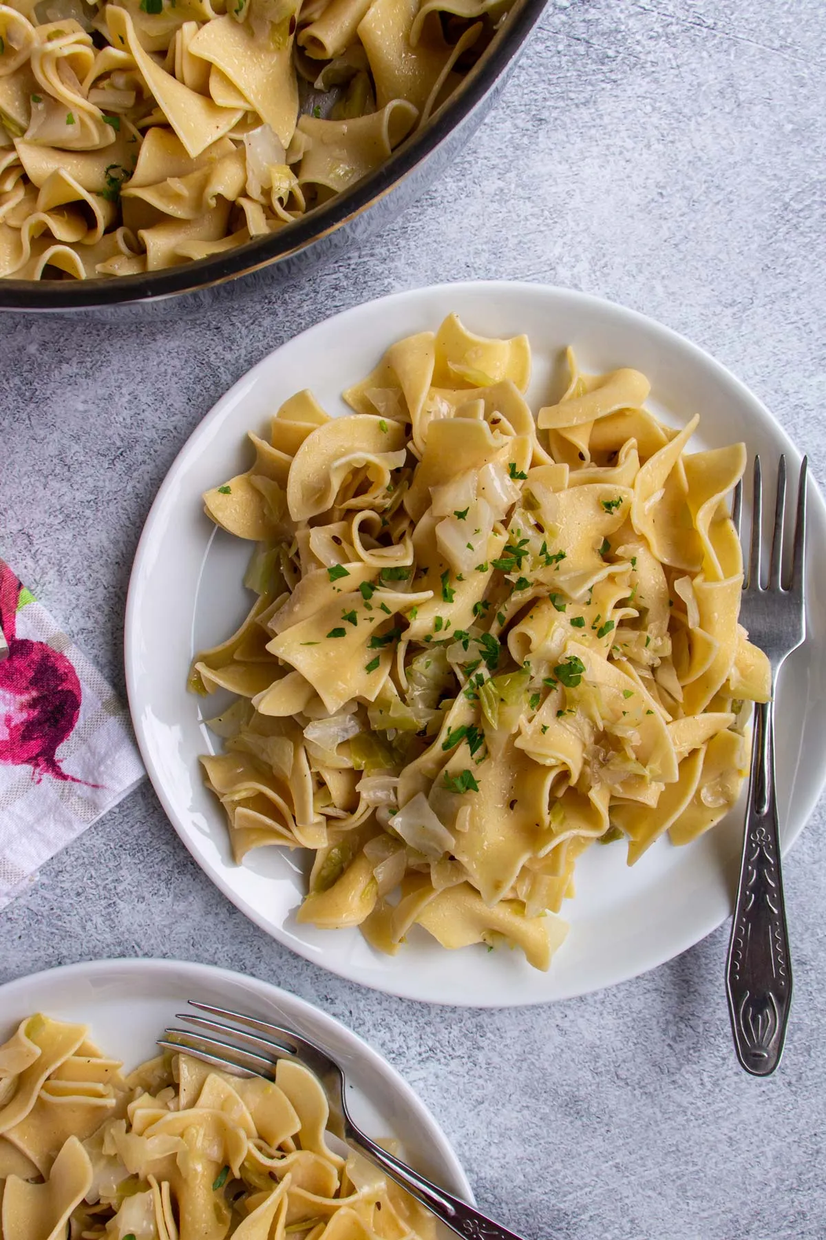 Krautfleckerl mit gehackter Petersilie auf einem weißen Teller mit Gabel.
