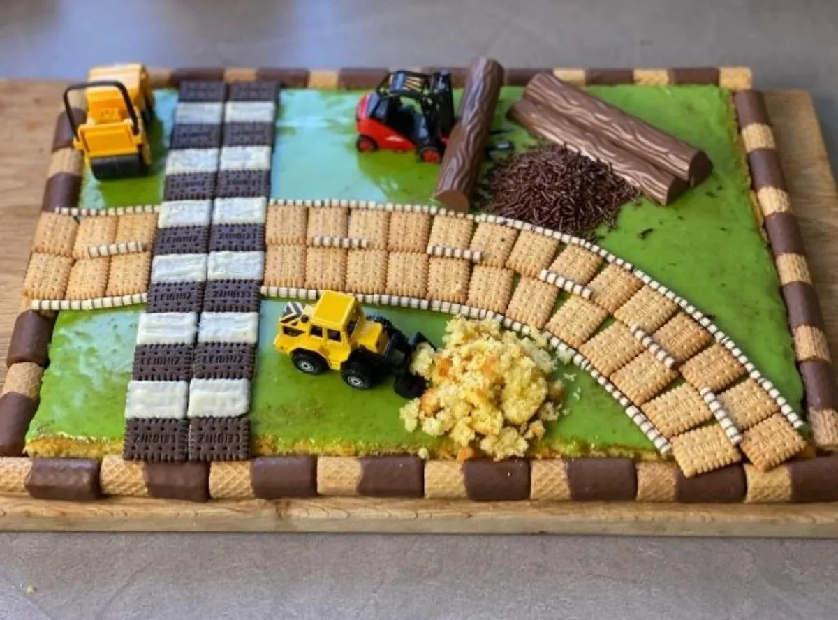 Kreativer Baustellen-Kuchen mit essbaren Baufahrzeugen und Schokostückchen, ein Hit für Jungen zum 3. Geburtstag.