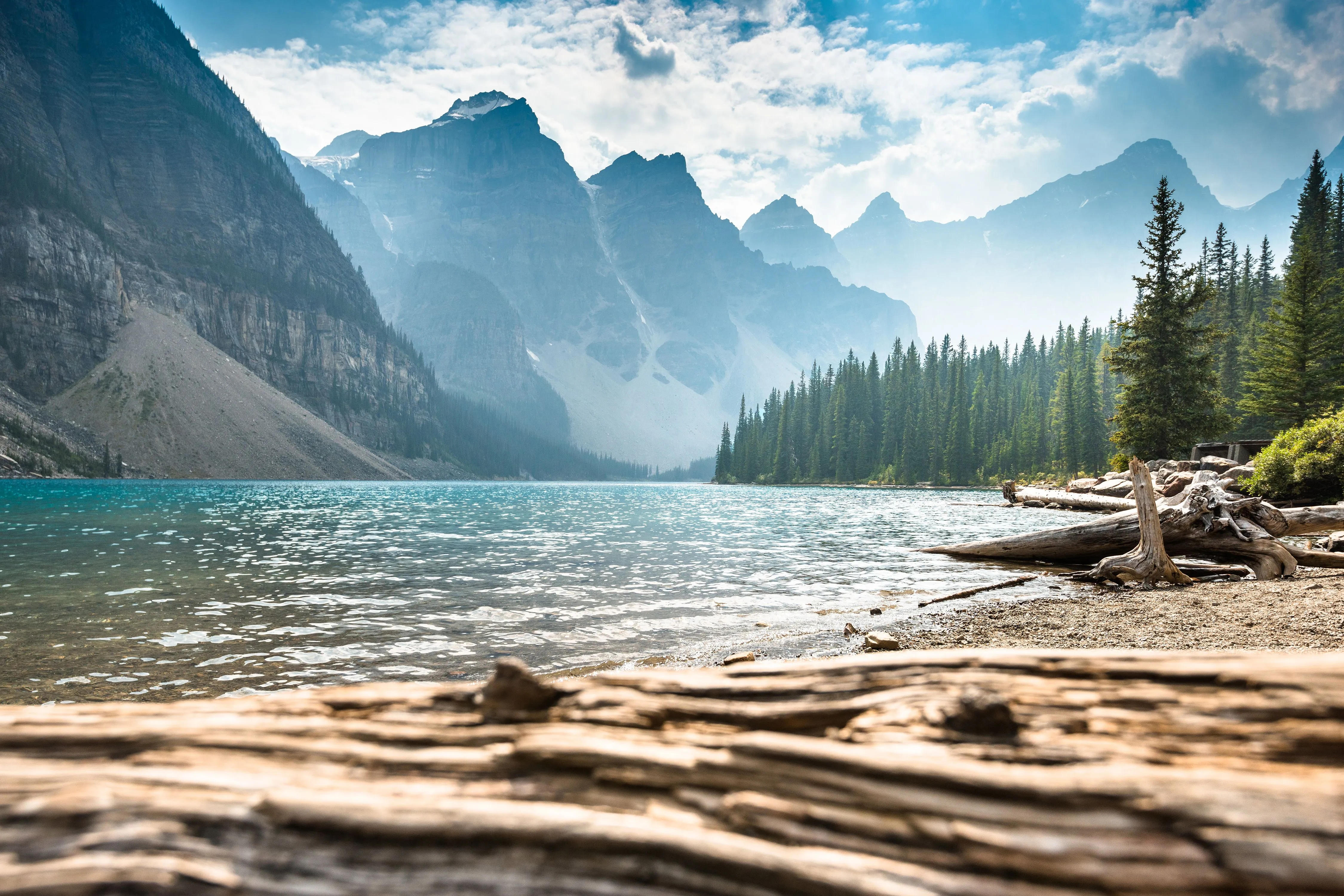 Kristallklarer Bergsee in Kanada mit riesigen nebelverhangenen Bergen und einem dichten Wald