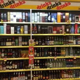 Kunde wählt aus einem breiten Sortiment an Bieren in einem gut beleuchteten deutschen Getränkemarkt