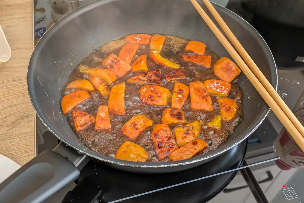 Kürbisstücke werden in der Nanbanzu-Soße geschwenkt, um sie gleichmäßig zu bedecken und anzudicken.