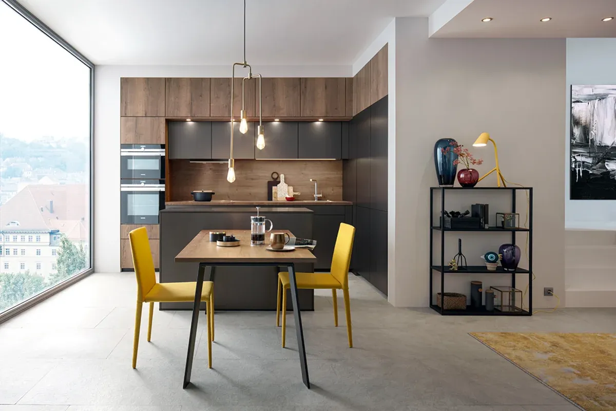 L-Förmige Küche im offenen Raum mit Fronten in grau und Holzoptik mit Esstisch und großer Deckenleuchte