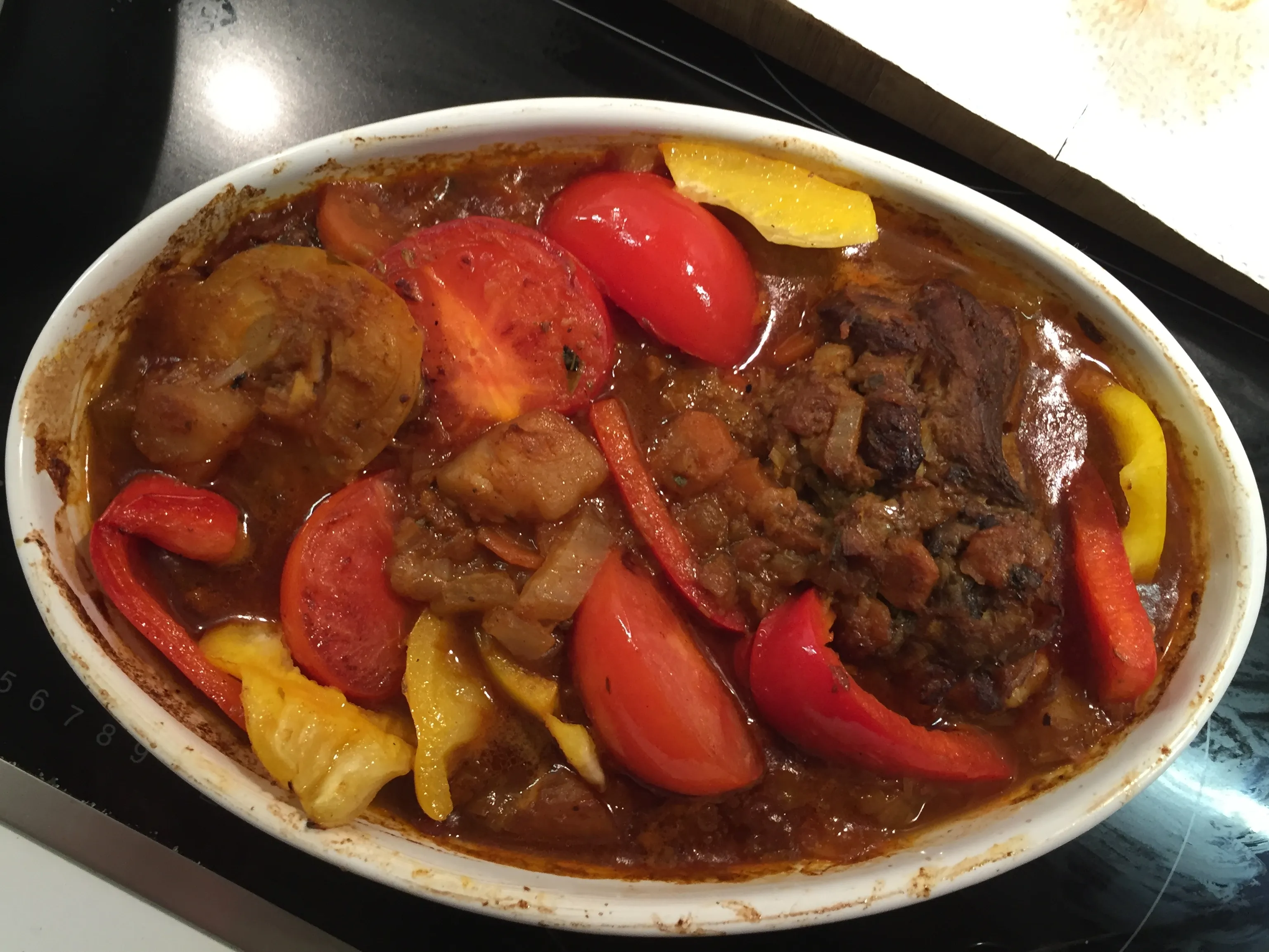 Lammhaxe und Gemüse schmoren langsam in einer Auflaufform im Ofen.