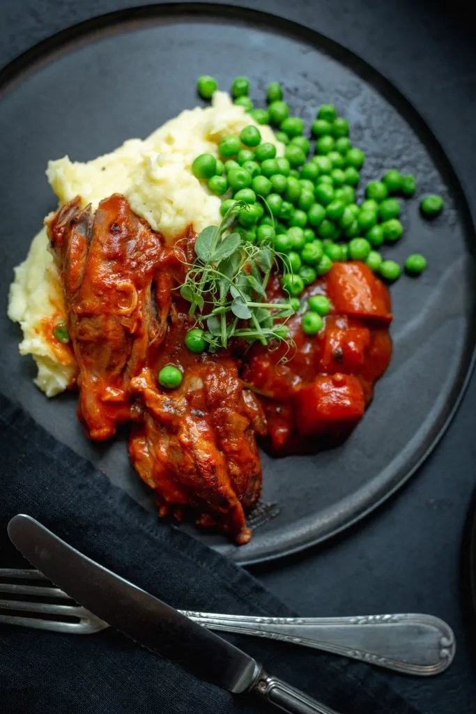 Lammstelzen brutzelnd im Schmortopf mit Gemüse und Rotwein, eine Basis für einfache Lamm Rezepte