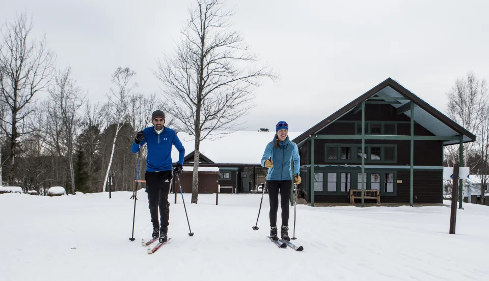 Langläufer auf breiter Loipe mit verschneiten Bäumen im Hintergrund