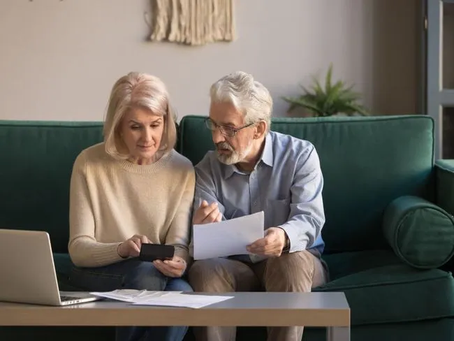 Lebensversicherung verkaufen: Ehepaar berät auf Couch über den Verkauf