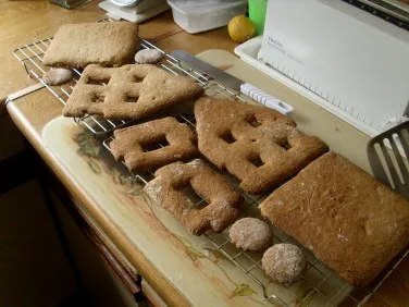 Lebkuchenteile, frisch aus dem Ofen, werden auf einem Kuchengitter abgekühlt, bereit für die Montage.