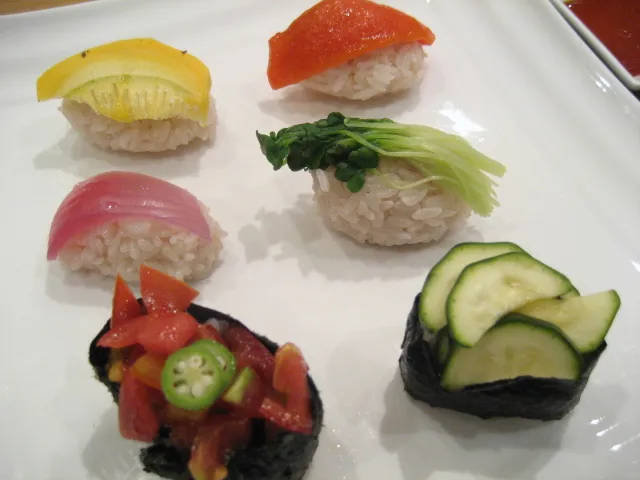 Leicht unscharfes Bild von vegetarischem Sushi mit marinierten Orangen und Tomaten