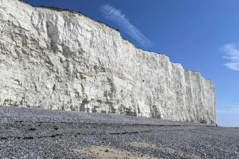 Leuchtend weiße Kreidefelsen hinter einem grauen Kiesstrand bei den Seven Sisters