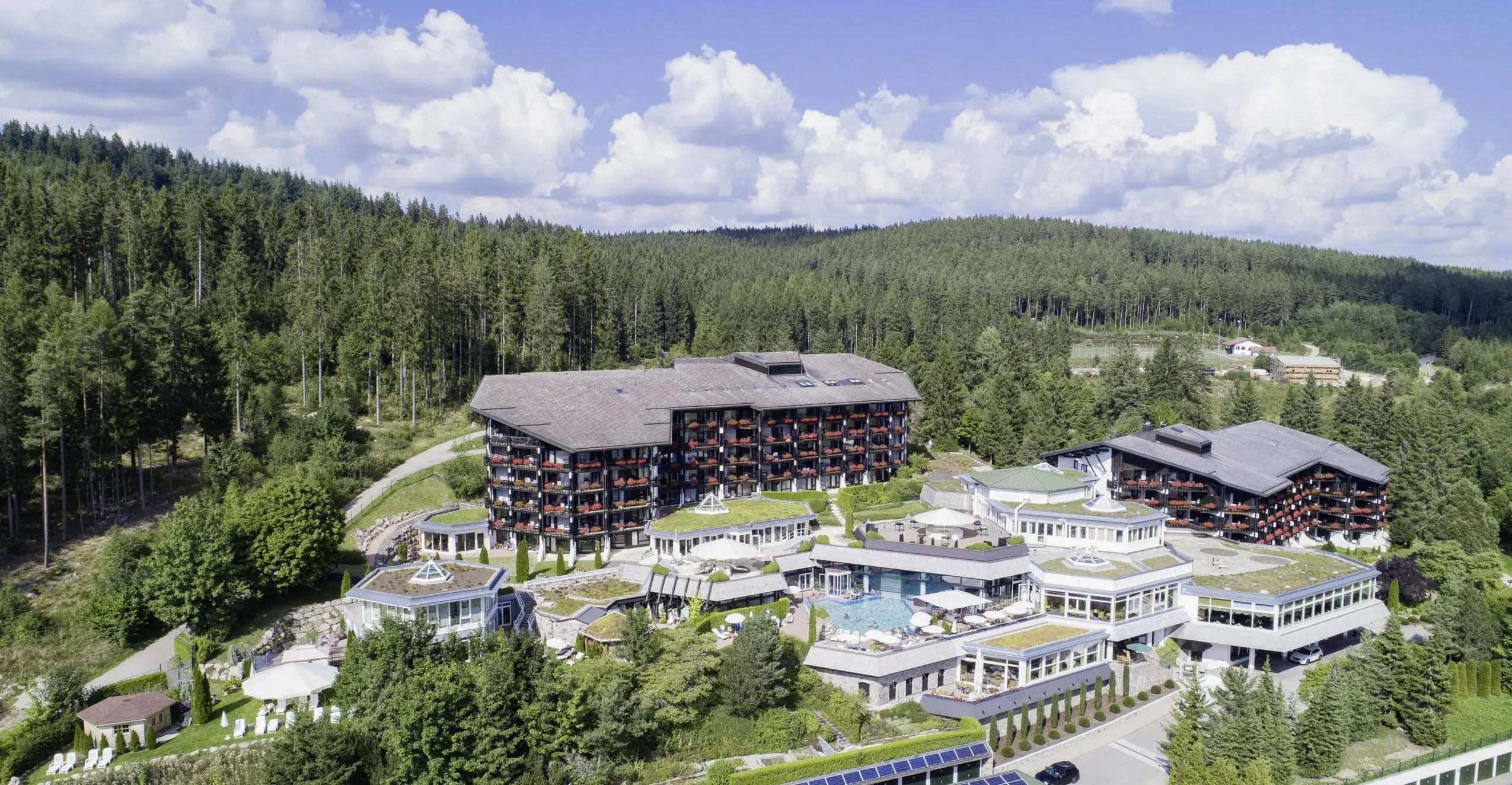 Luftaufnahme des weitläufigen Urlaubsresorts Vier Jahreszeiten am Schluchsee, eingebettet in die grüne Landschaft des Schwarzwaldes, perfekt für einen aktiven Urlaub mit Hund.