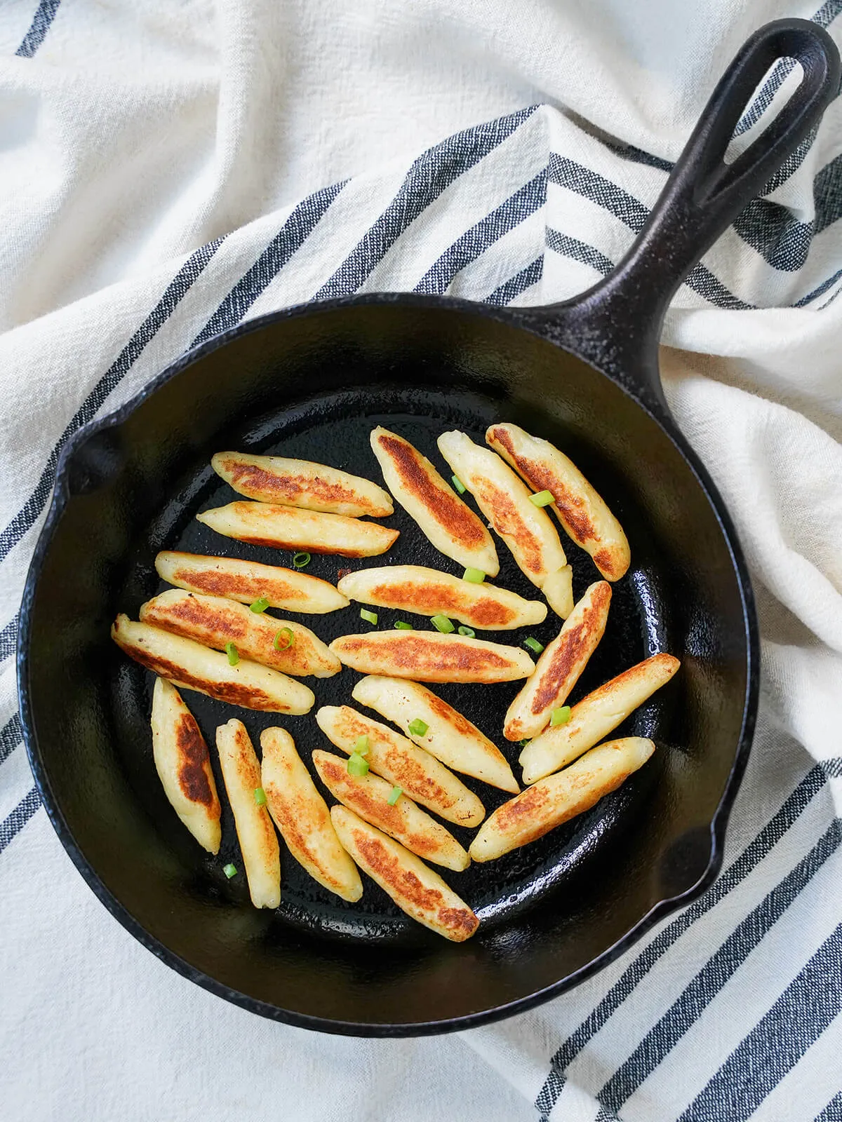 Luftaufnahme einer Pfanne voller goldbraun gebratener Schupfnudeln