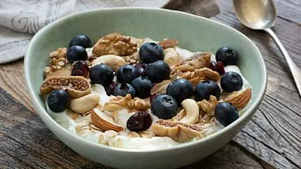Magerquark mit frischen Blaubeeren und knackigen Nüssen als sättigender Snack für eine kalorienarme Ernährung.