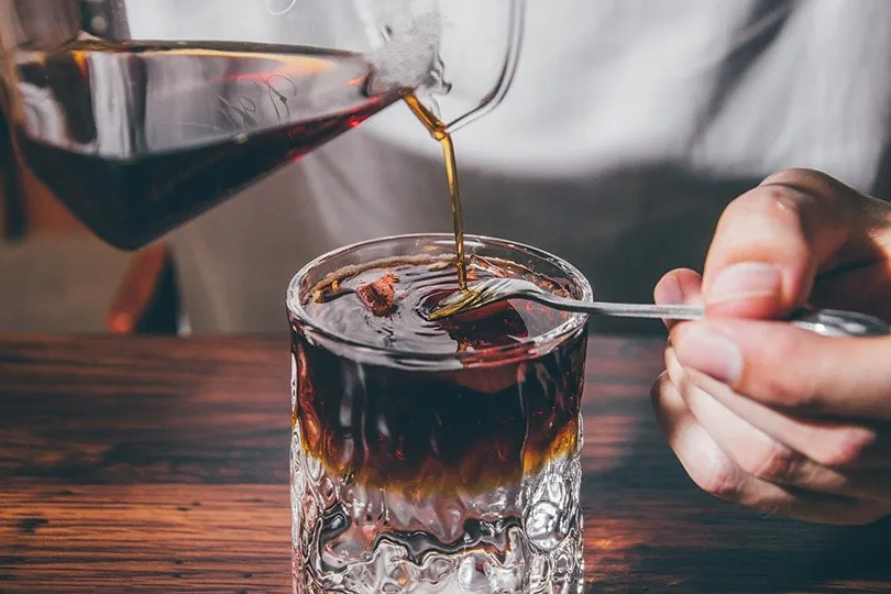 man pouring coffee in a glass