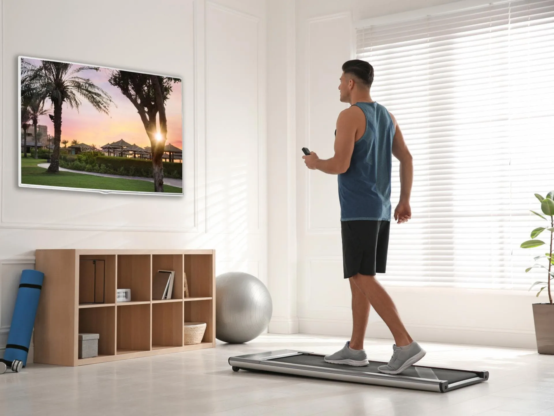 Mann geht auf kleinem Laufband im Wohnzimmer spazieren