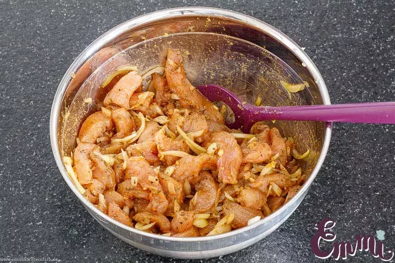 Mariniertes Gyrosfleisch in einer Schüssel mit Zwiebeln und Gewürzen