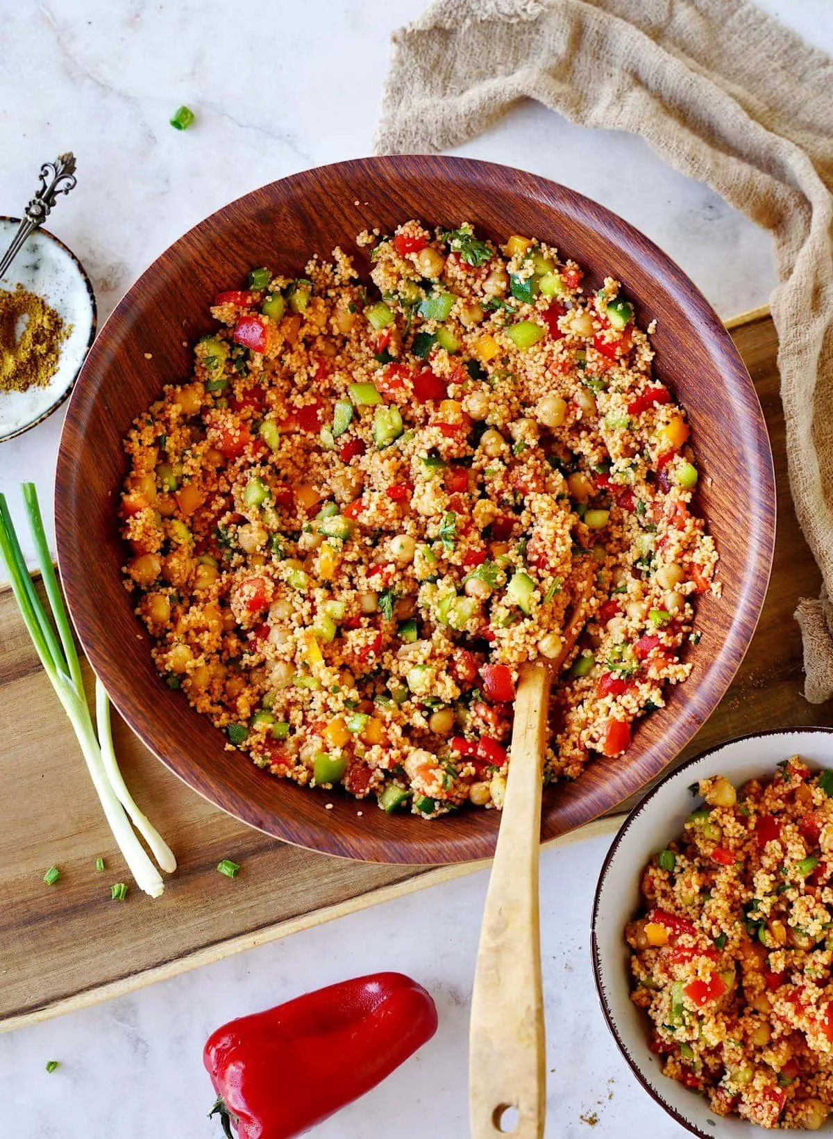 Marokkanisch inspirierter Couscous-Salat mit Ras El Hanout-Dressing und knackigem Gemüse in einer Holzschüssel, ein gesundes veganes Mittagessen.