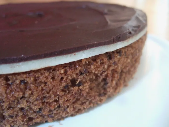 Marzipandecke wird mit Schokoladen-Ganache bestrichen, vorbereitet für die Torte.