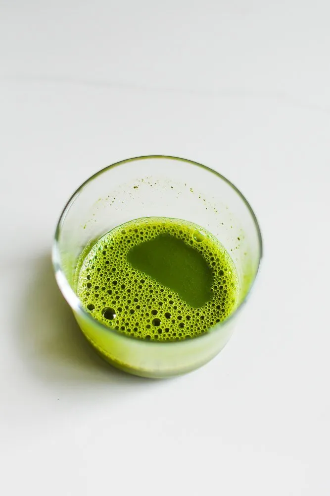 Matcha, in heißem Wasser gelöst, in einem kleinen Glas.