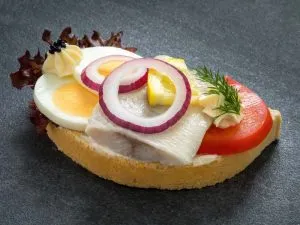 Matjesfilet auf einem Brötchen mit Zwiebelringen