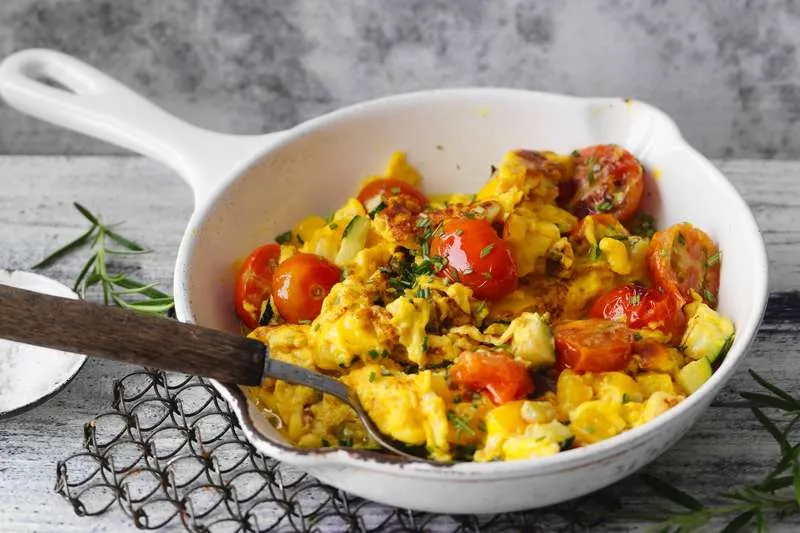 Mediterranes Rührei als proteinreiches Frühstück zum Abnehmen mit frischen Kräutern und Tomaten