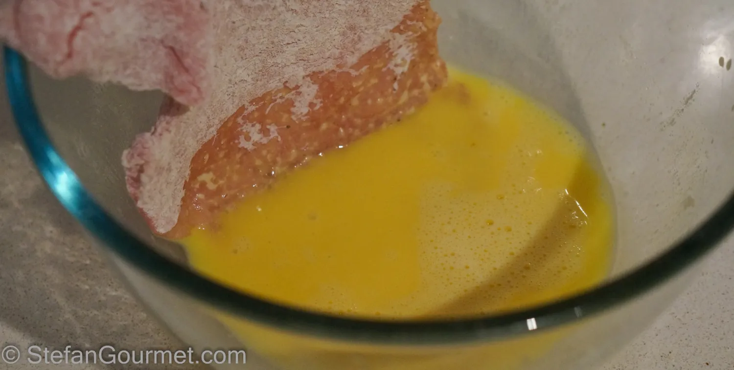Mehl-paniertes Schnitzel in der Ei-Milch-Mischung