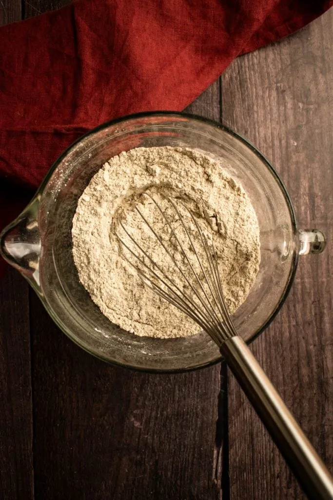 Mehl und trockene Zutaten mit einem Schneebesen in einer Rührschüssel.