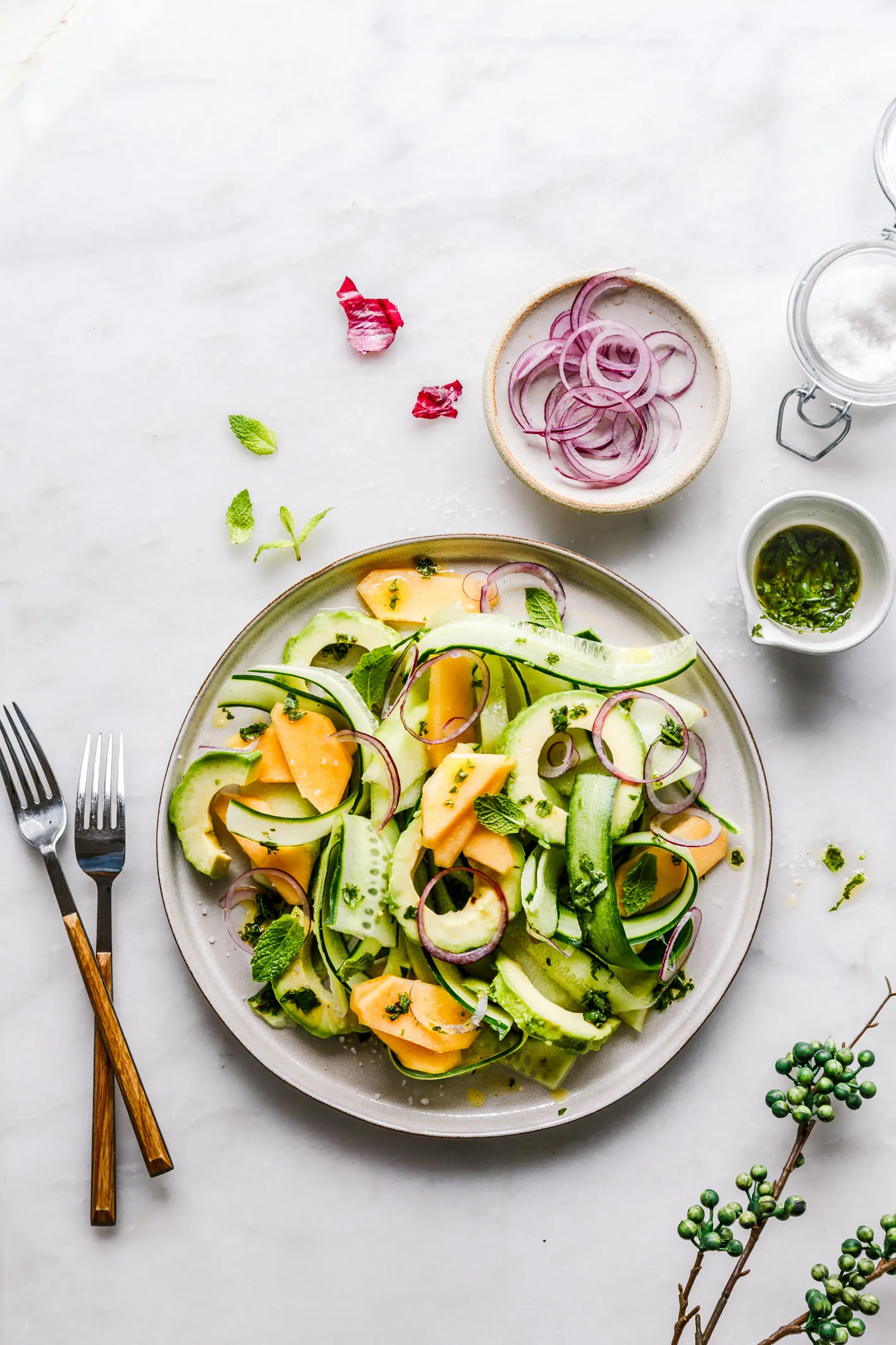 Melonen-Gurken-Salat auf Teller mit Besteck und roten Zwiebeln