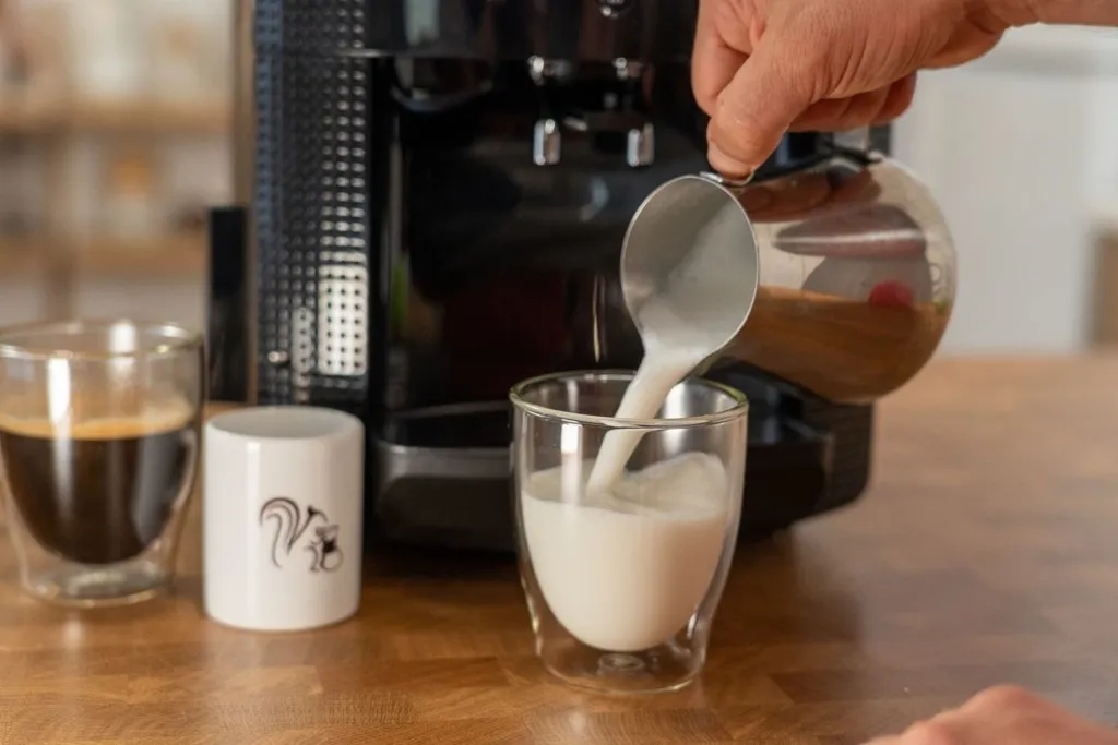 Milchschaum aus der Krups in eine Tasse gießen
