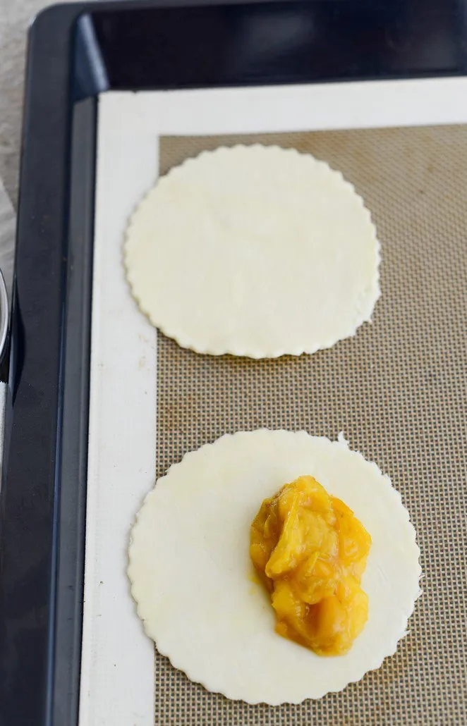 Mirabellenkompott wird auf Blätterteigkreise verteilt