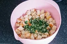 Mischung aus Brötchenwürfeln, warmer Milch, Zwiebeln und Petersilie zieht für die Knödelmasse